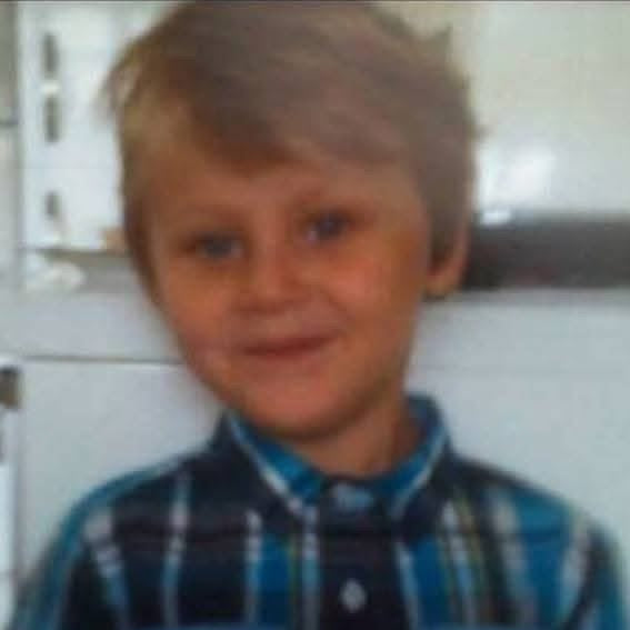 Unrestored photo of a Young boy wearing a blue plaid shirt in an indoor setting